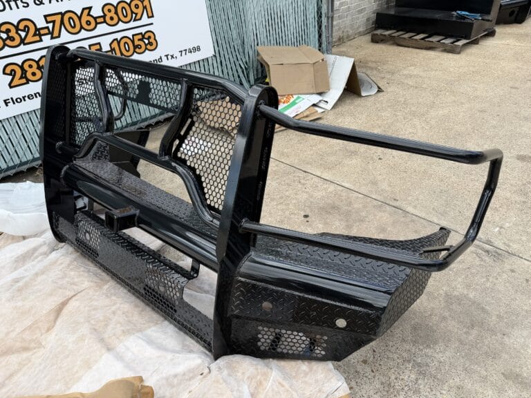 Aftermarket grill-guard bumper next to the Texas Truck Parts sign showing the Sugar Land address and phone number